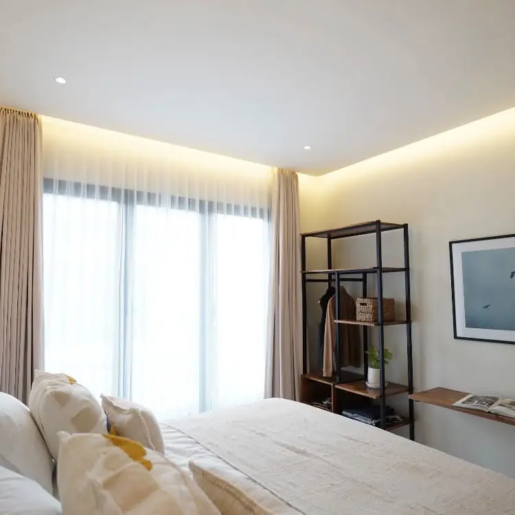 Bedroom with soft linen, warm cove lighting and full-height curtains