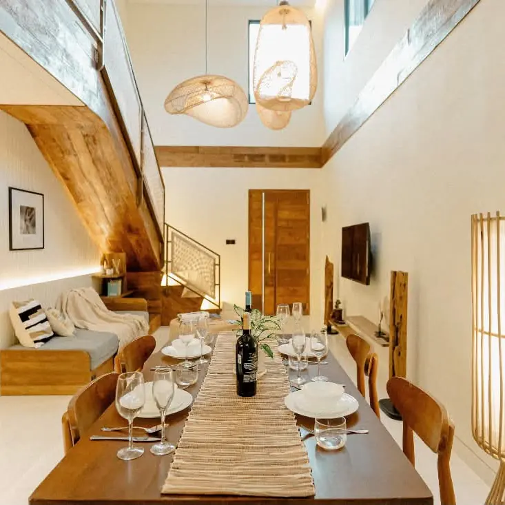 Dining table set for six under woven pendant lights in a furnished villa